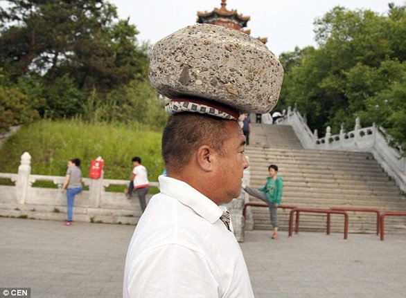 صيني يحمل حجراً على رأسه ليخسر الوزن الزائد