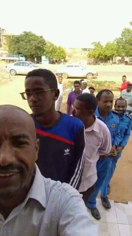 ضباط بالشرطة السودانية يقفون مع المواطنين في الصف