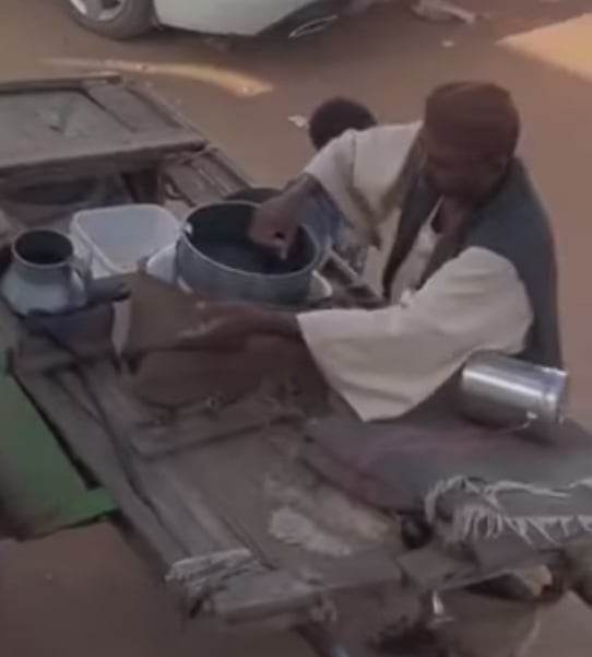 شاهد بالصورة والفيديو.. رغم صوت الرصاص واشتعال النيران أمامه.. بائع لبن سوداني يتجول بحماره داخل الأحياء ويقوم بتوصيل الحليب للزبائن أمام منازلهم والاشادات تنهال عليه 10 بائع لبن